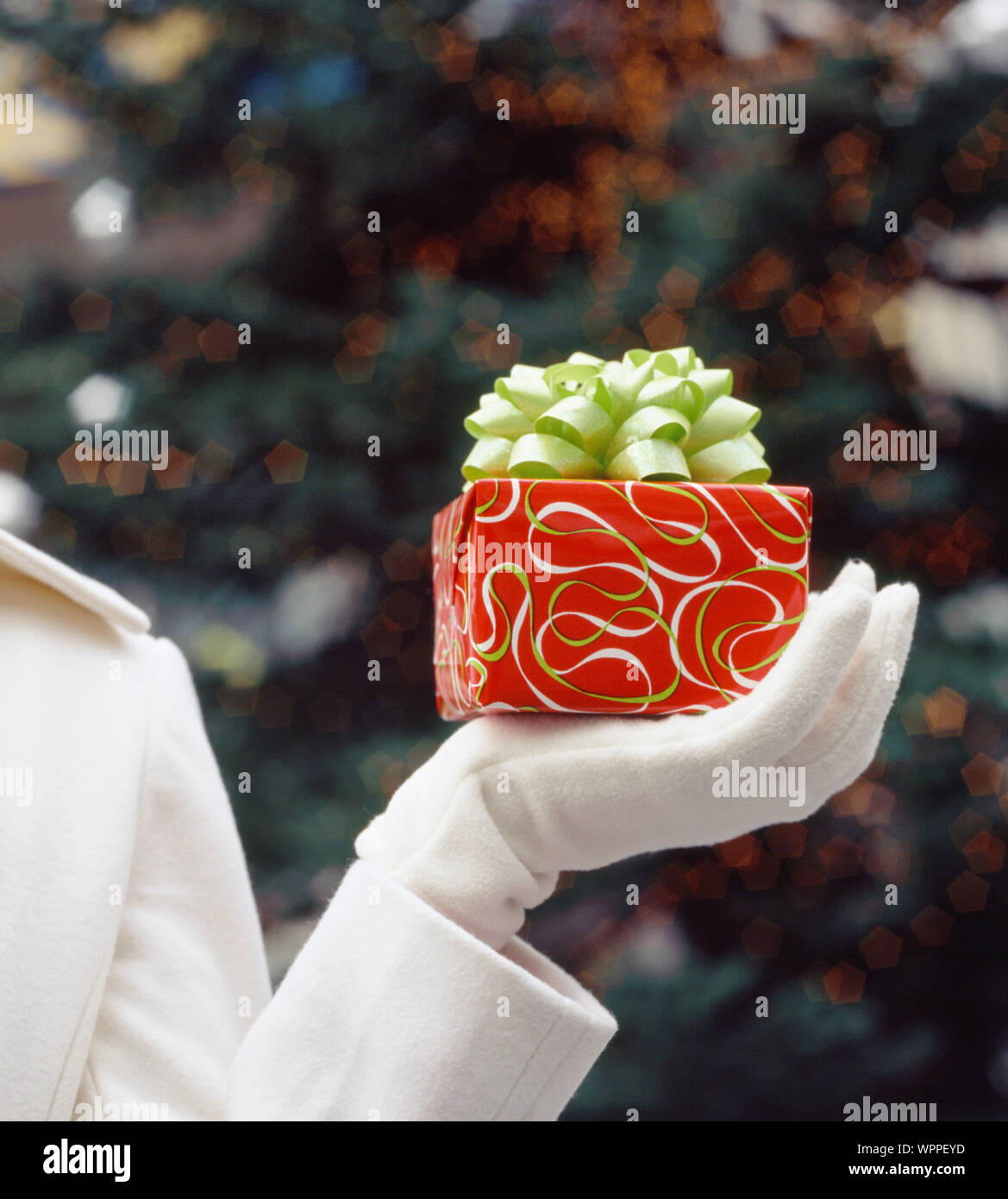 Woman's Hand mit Geschenk in festliches Geschenkpapier und Bogen gewickelt. Urlaub Geschenke Geschenke Hintergrund. Stockfoto