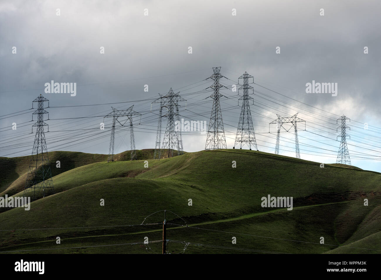 Üppig grüne Hügel rahmen Reihen von Stromleitungen westlich von Modesto im kalifornischen San Joaquin Valley Stockfoto