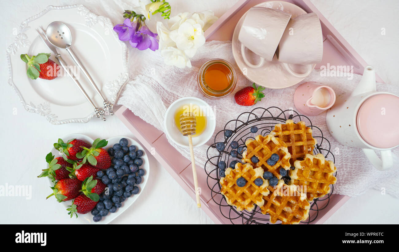 Moderne Blush Pink Frühstück mit Waffeln, Honig und Obst. Stockfoto