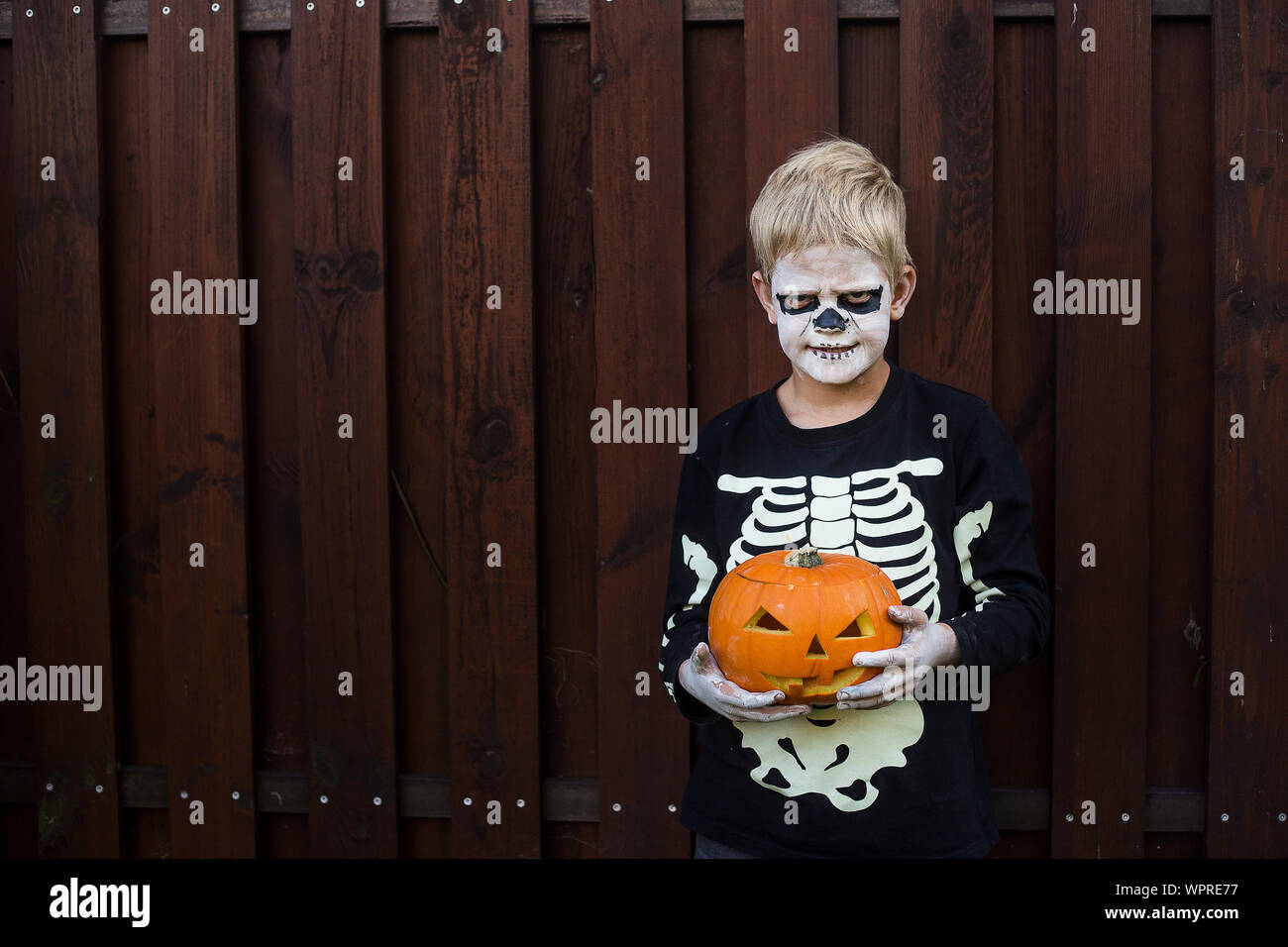 Glückliche junge blonde Haare Junge mit Skelett Kostüm Holding jack o lantern. Halloween. Trick oder Festlichkeit. Im Freien portrait Stockfoto