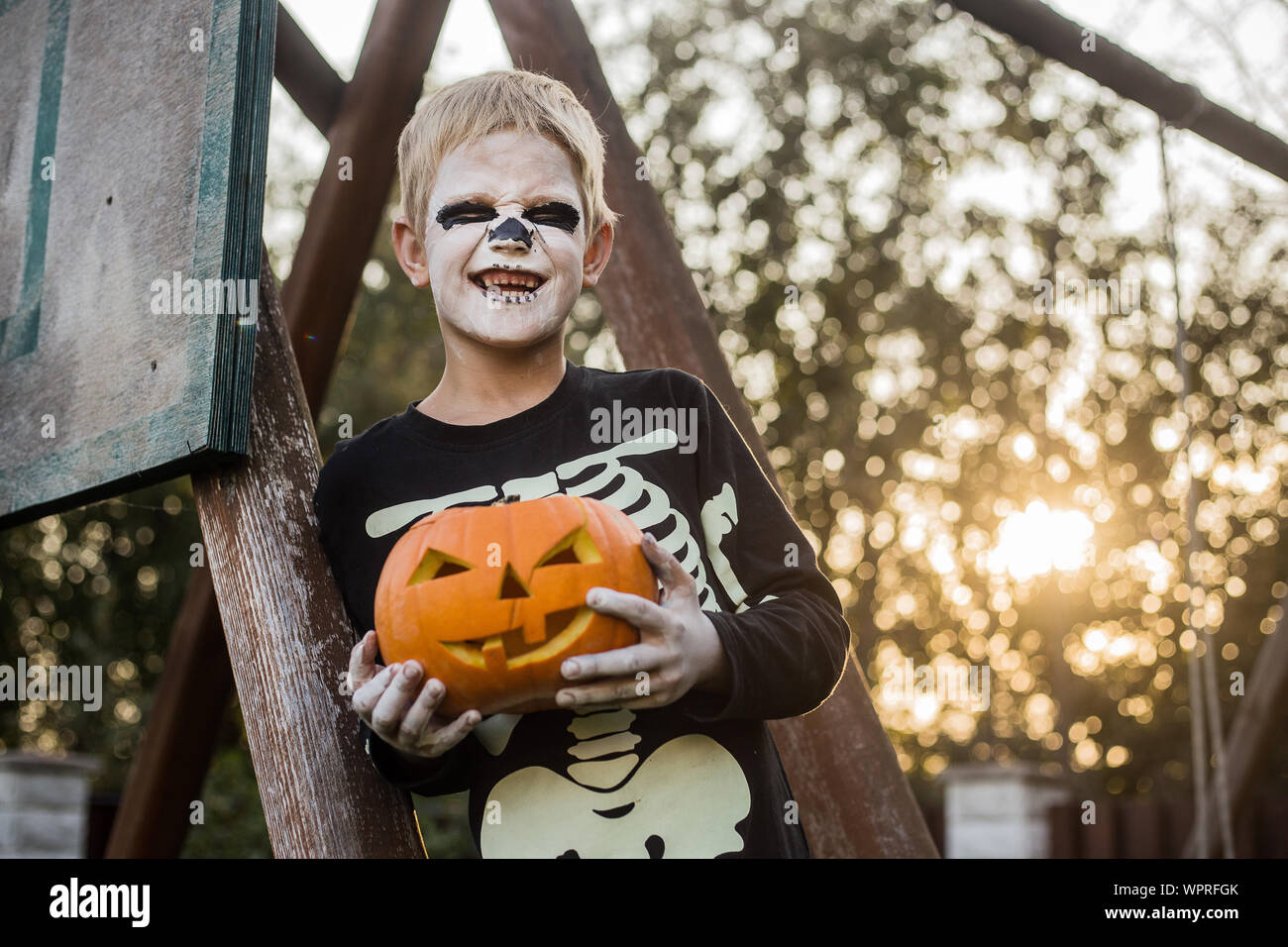 Glückliche junge blonde Haare Junge mit Skelett Kostüm Holding jack o lantern. Halloween. Trick oder Festlichkeit. Im Freien portrait Stockfoto