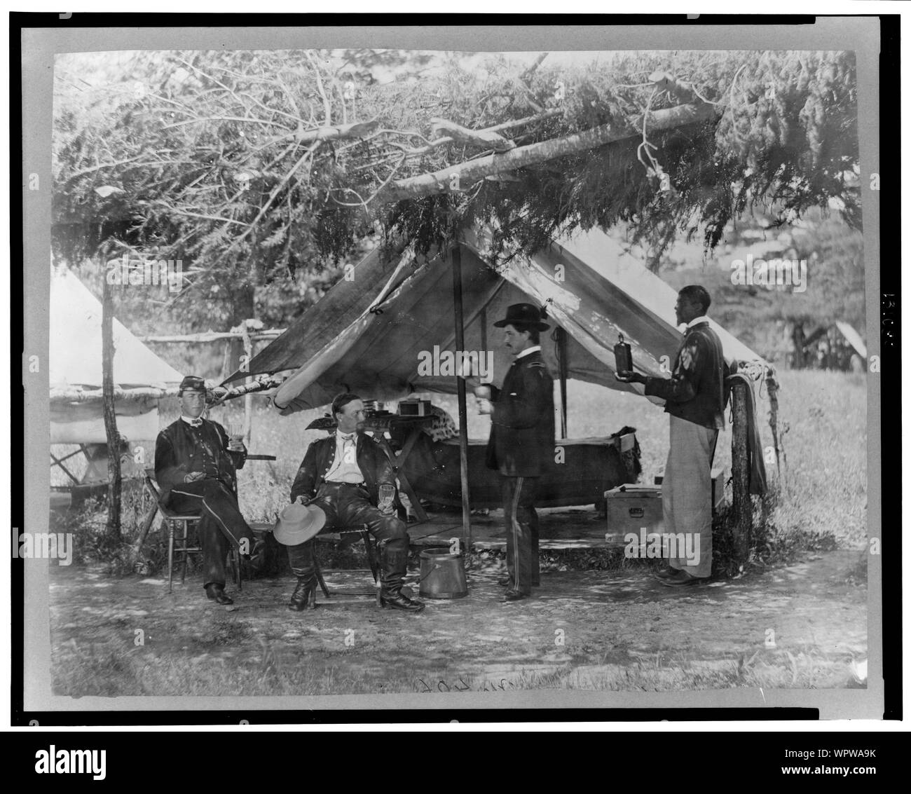 Maj. S.H. Humphrey und andere Abstract: Drei Bürgerkrieg Union Soldaten, trinken Außerhalb einer überdachten Wohnbereich, African American auf der rechten Holding Flasche. Stockfoto
