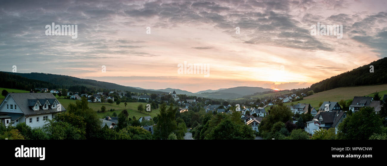 Weiten Panoramablick über die bergige Spa Village von Grafschaft im Winter Sport Region Sauerland, Deutschland, bei Sonnenuntergang mit einer teilweise colo Stockfoto