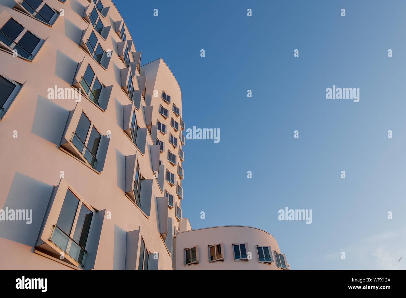 Ansicht der Krümmung Form der weißen Fassade Fassade mit rechteckigen Fenstern, von ikonischen Architektur an Madiahafen während des Sonnenuntergangs Zeit und Dämmerung Himmel. Stockfoto