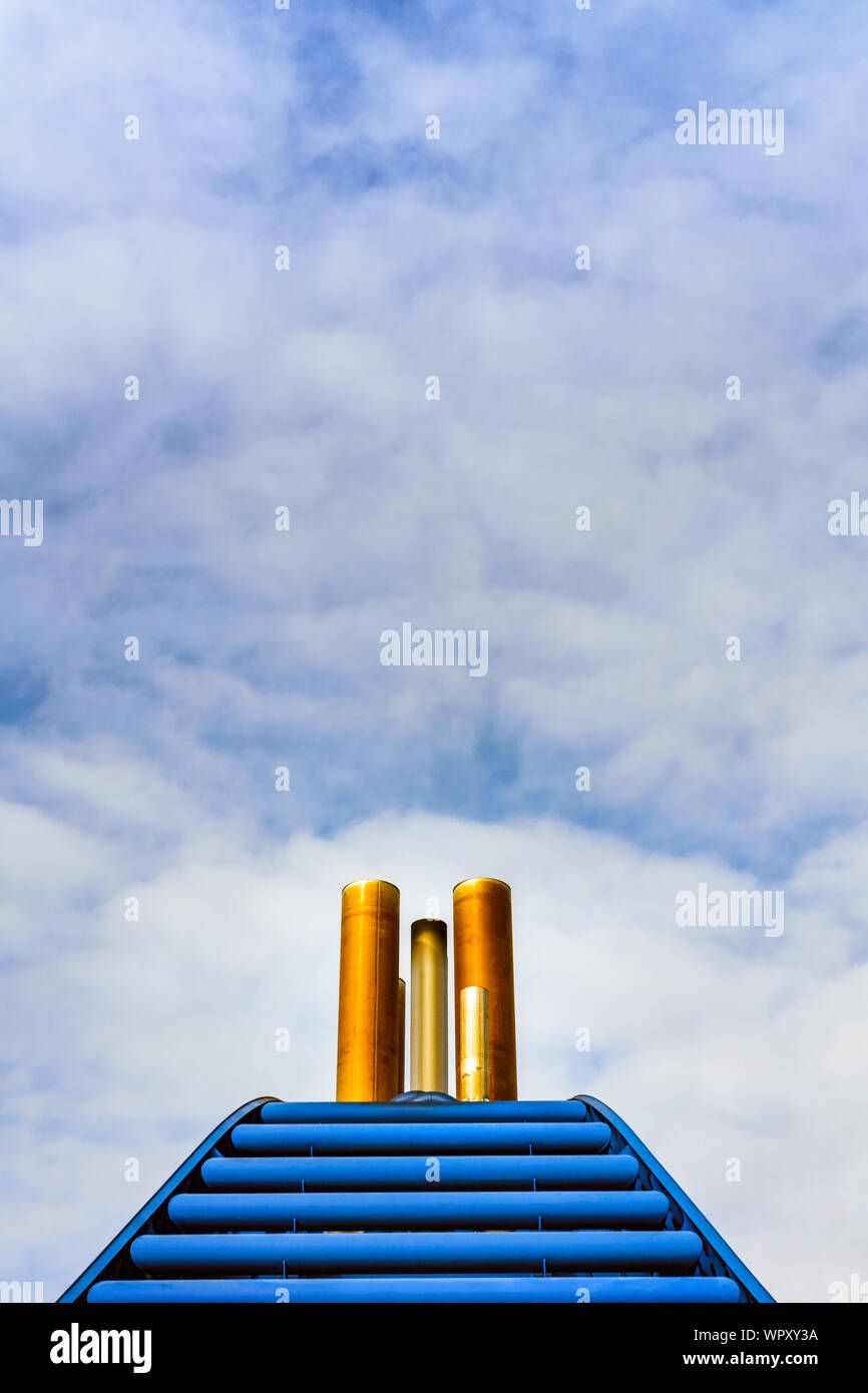 Einfache grafische Vorderansicht der rostigen Schiff Auspuffrohre und blaue Verkleidung gegen den blauen Himmel mit Wolken. Stockfoto