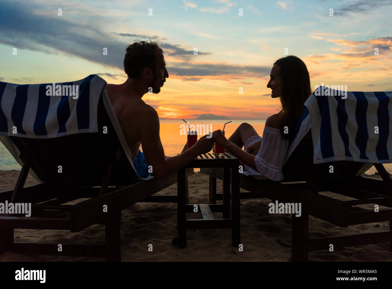 Paar trinken Cocktails am Strand bei Sonnenuntergang während Urlaub oder Flitterwochen Stockfoto