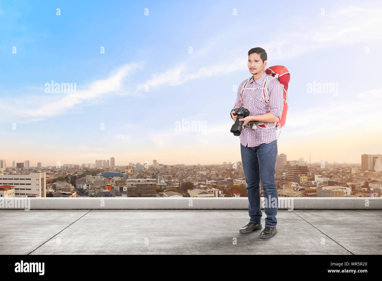 Asiatischer Mann mit einem Rucksack mit einer Kamera auf dem Dach des Gebäudes zu nehmen Stockfoto