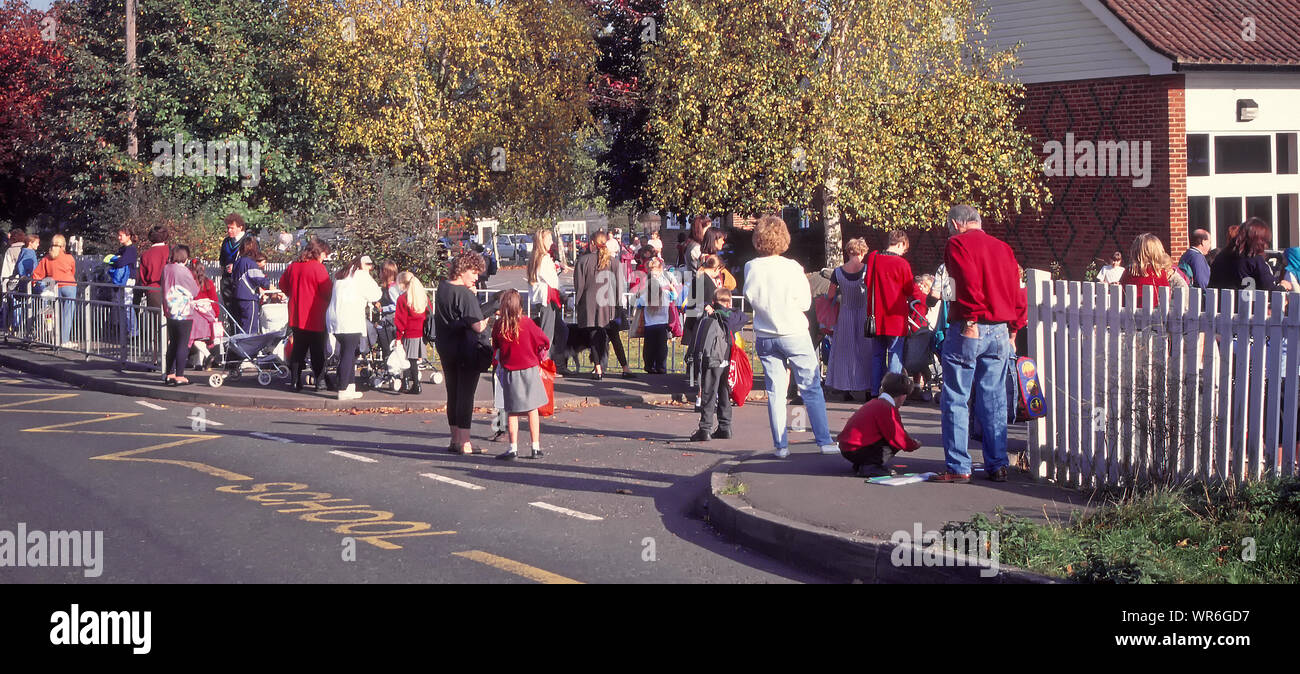 Bildung für Grundschüler Eltern warten Junge&Mädel Schülerinnen von außerhalb Dorfschule Tore klar von der Schule zu sammeln laufen Parkplatz UK Stockfoto
