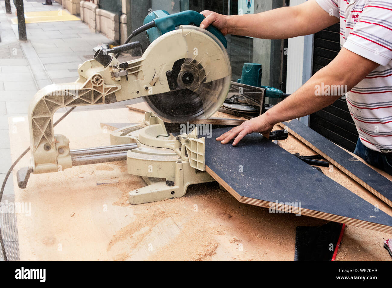 Männliche Tischler Hände schneiden Schichtplatten mit einer Kreissäge in der Straße. Stockfoto