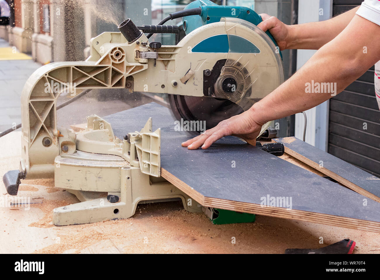 Männliche Tischler Hände schneiden Schichtplatten mit einer Kreissäge in der Straße. Stockfoto