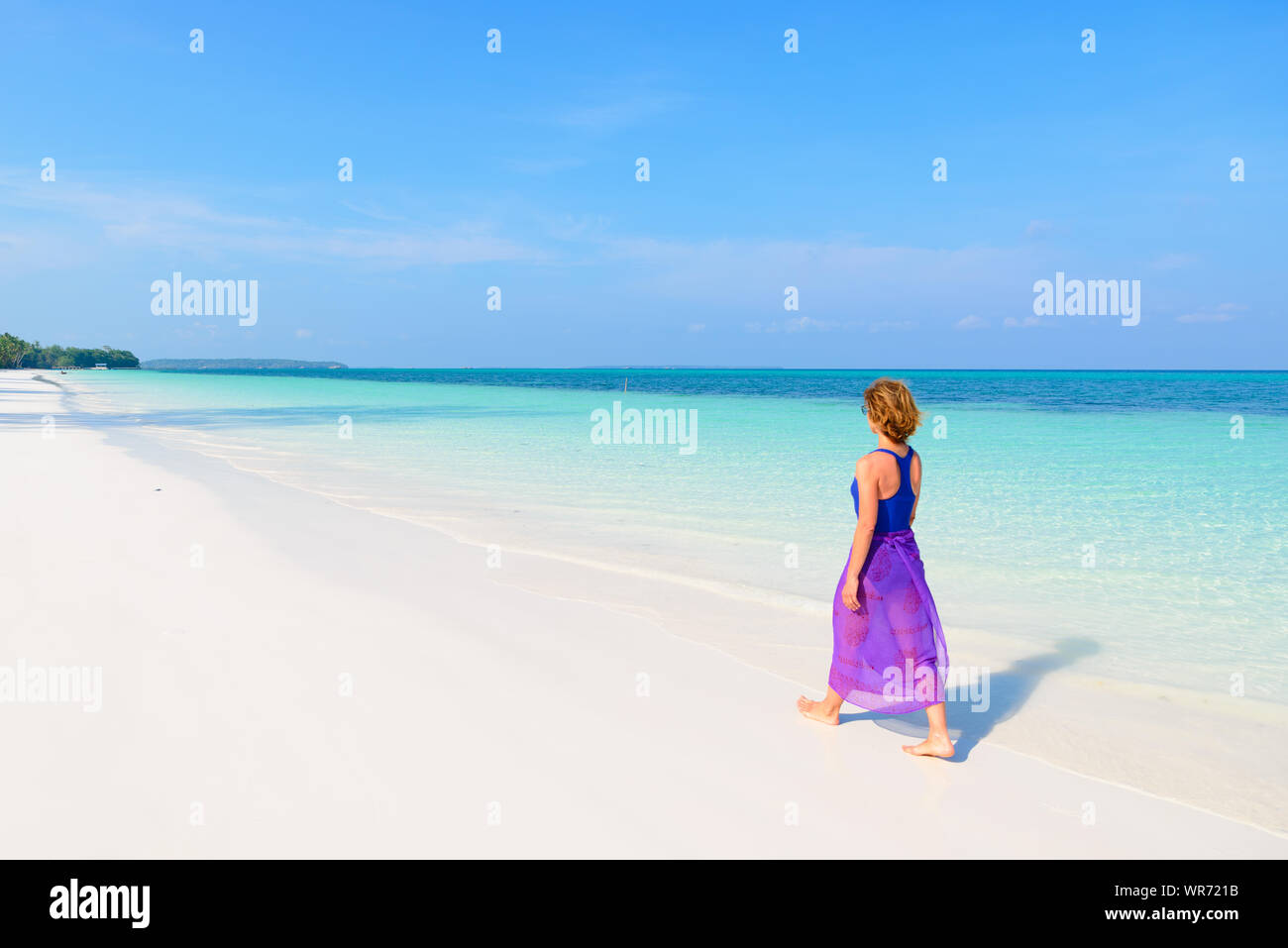 Frau Wandern am tropischen Strand. Ansicht der Rückseite White Sand Beach türkis durchsichtig Wasser Karibik reale Menschen. Indonesien Kei Inseln Molukken trave Stockfoto