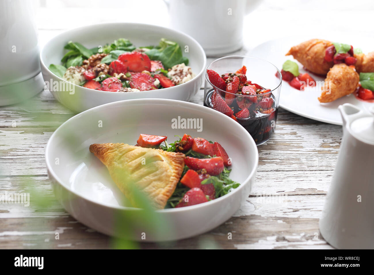 Erdbeere Menü. Blätterteig mit Ricotta, Rucola, Quark und Erdbeere, Salat, Erdbeeren in Aceto Balsamico mit grünem Pfeffer, Erdbeere Pfannkuchen Stockfoto