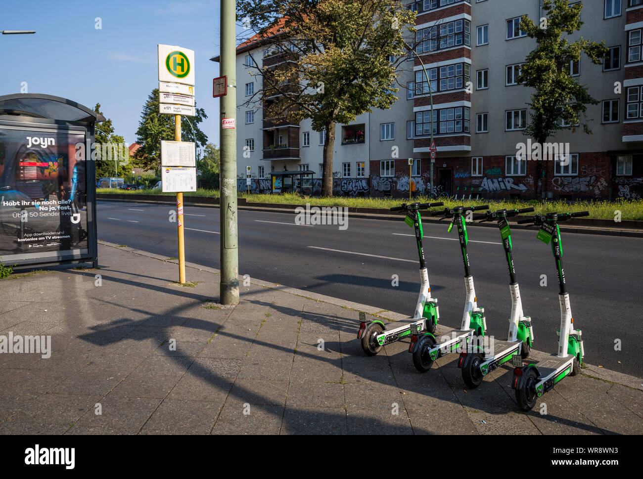 Kalk e-Scooter an einer Bushaltestelle im Bereich Berlin Neukölln geparkt, Deutschland Stockfoto