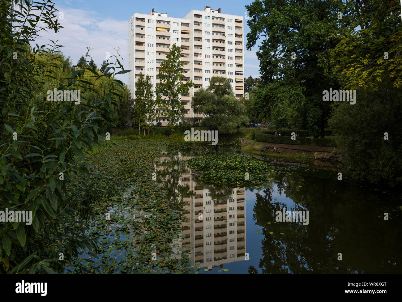 Ein Wohnblock spiegelt sich in einem Teich im Lindenhofer Park in Schoneberg, Berlin, wider Stockfoto