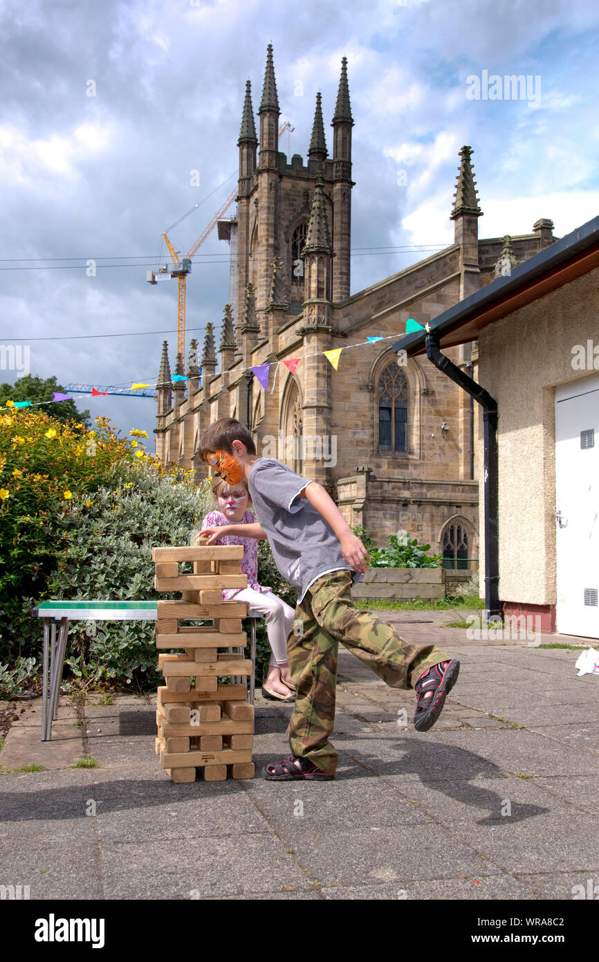 Sheffield, Yorkshire, Großbritannien - 1 August 2016: Spaß für die ganze Familie Tag - ein gelangweilter Schwester Uhren ihr Bruder spielen Riesen Jenga am 1. Aug. In der St. Mary's Church Family Fun Stockfoto