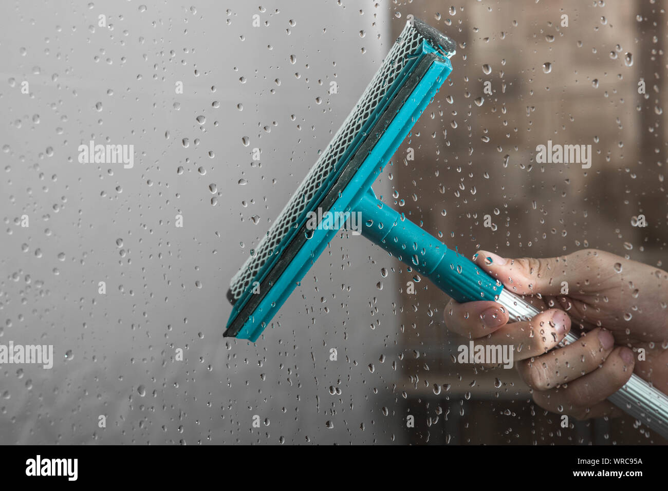 Nahaufnahme Reinigung dusche Glastür mit Rakel Stockfoto
