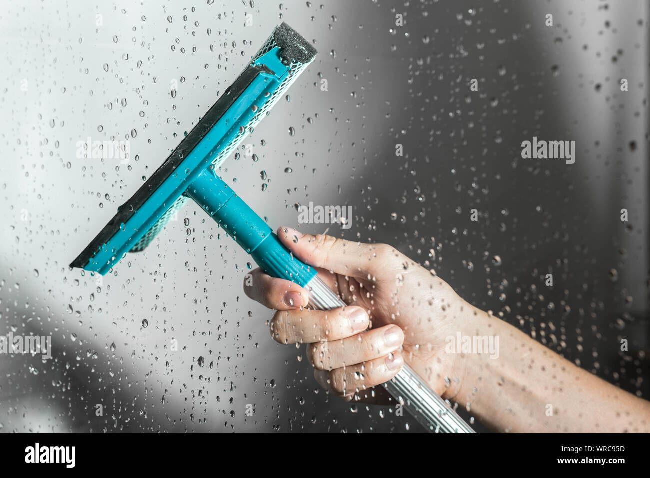 Nahaufnahme Reinigung dusche Glastür mit Rakel Stockfoto