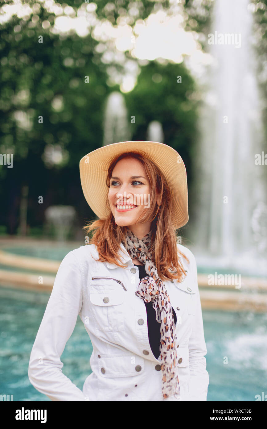 Glückliche junge stilvolle Frau im Park lächelnd mit Brunnen im Herbst Stockfoto