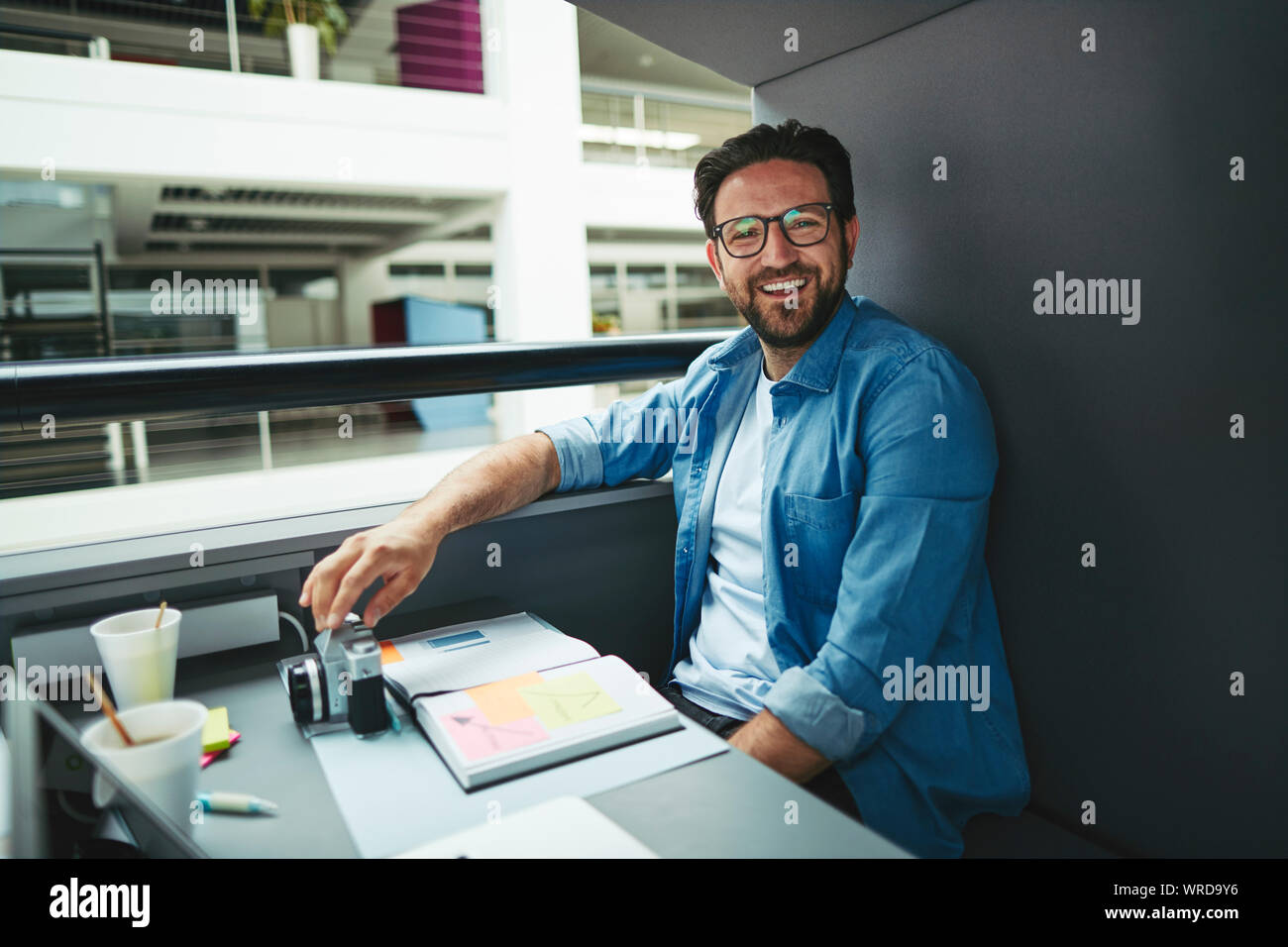 Lachend Creative Professional über Noten und arbeitet an einem Laptop, während allein in einem Büro pod Stockfoto