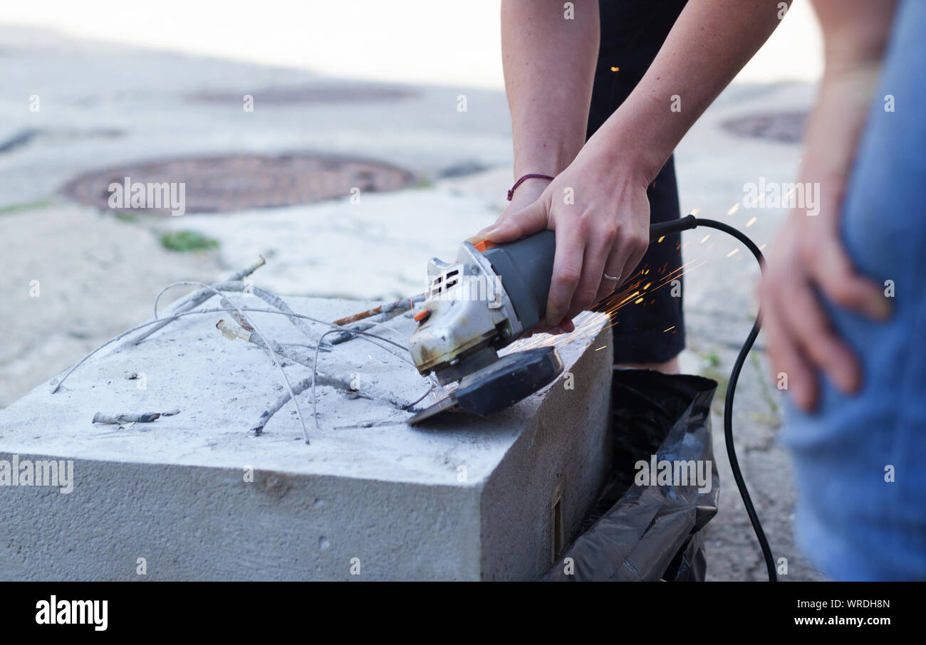 Frau trennt, Metall mit einer Trennscheibe. Einhand Winkelschleifer. Flex von Beton Stockfoto