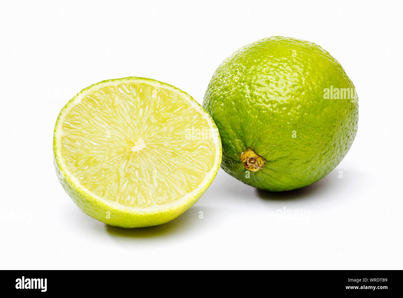Grüne Limone, eine ganze und eine halbe Limetten auf weißem Hintergrund Stockfoto