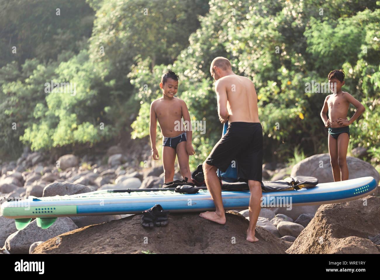 Asiatische Boys auf Surfbrett in der Nähe des Flusses Stockfoto