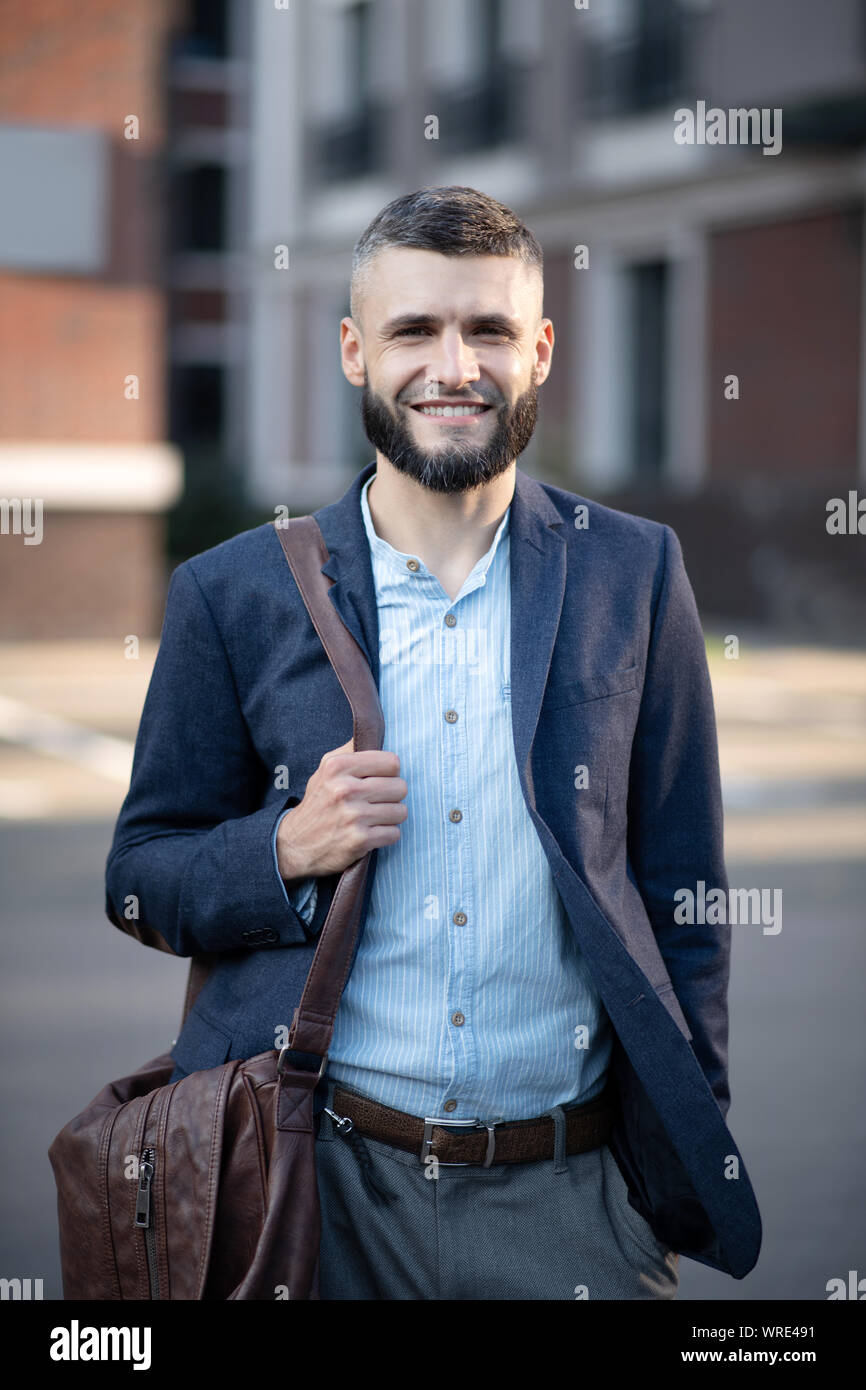 Strahlende Geschäftsmann mit braunem Leder Tasche draußen stehen Stockfoto
