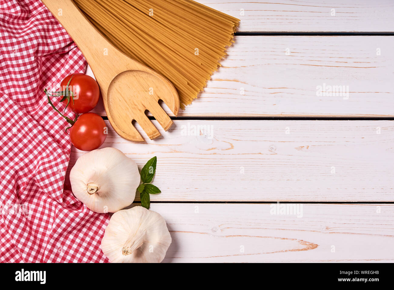 Aus holzbrettern von weißer Farbe mit roter Schale und Spaghetti, Tomaten und Knoblauch und mit Platz für Text, Hintergrund. Stockfoto