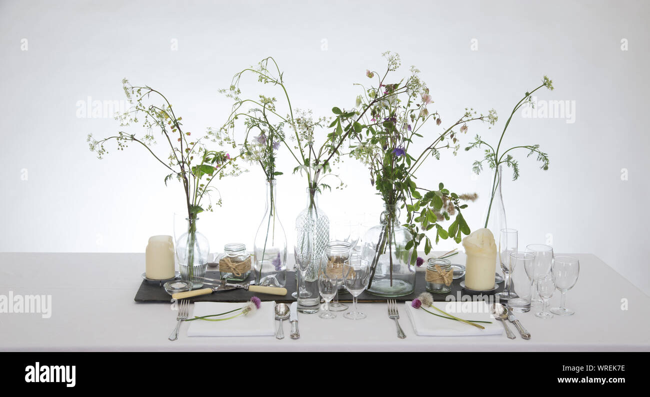Tabelle Einstellung mit klarem Glas, andles und einfache Blumenschmuck. Stockfoto