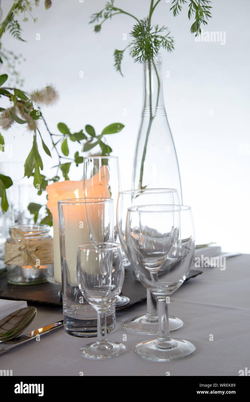 Tabelle Einstellung mit klarem Glas, andles und einfache Blumenschmuck. Stockfoto