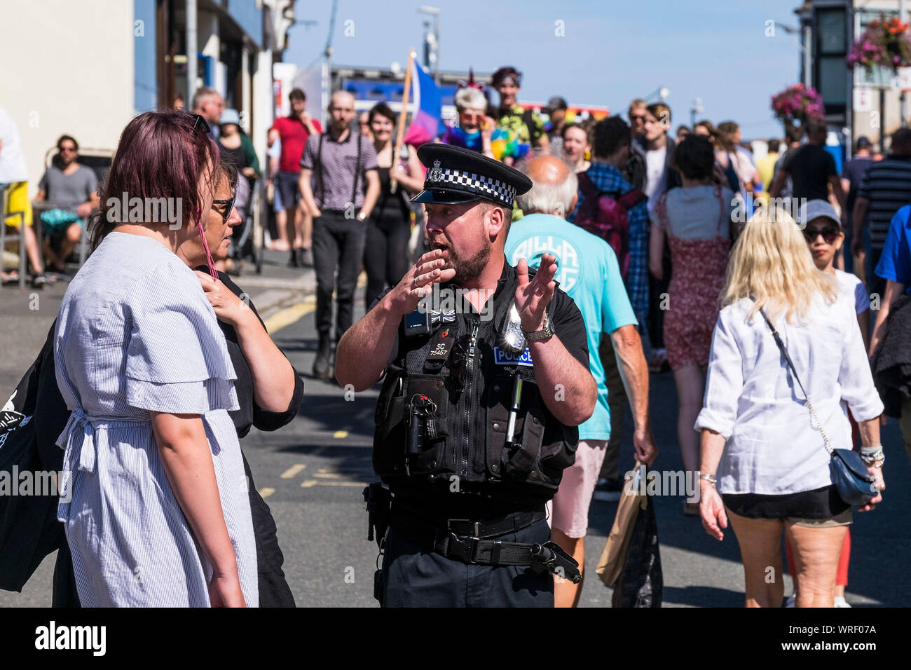 Ein Polizist der Polizei von Devon und Cornwall hilft Urlaubern in Newquay Town in Cornwall. Stockfoto