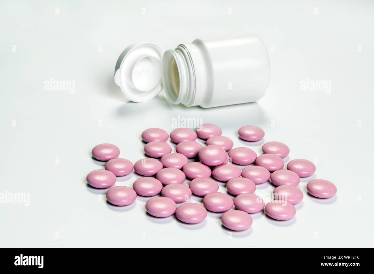 In der Nähe von Rosa Tabletten und medizinische Flasche auf weißem Hintergrund Stockfoto