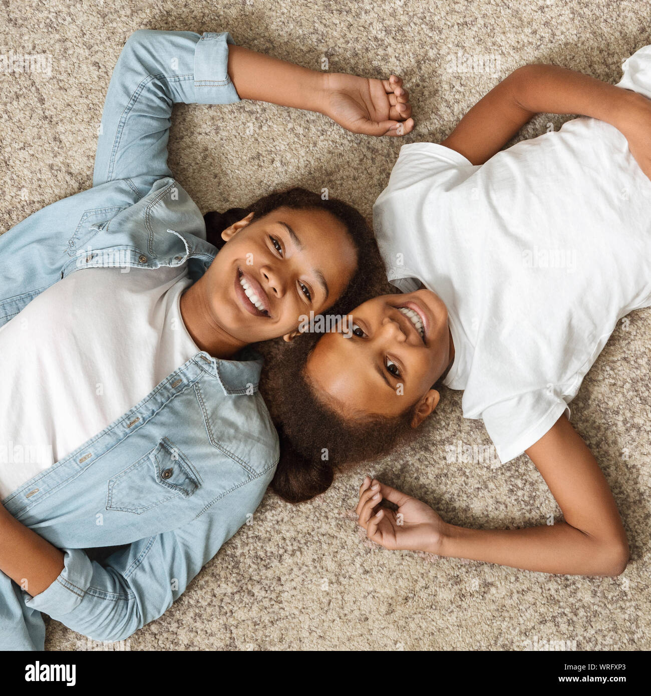 Porträt von zwei fröhlichen Schwestern Festlegung auf dem Boden Stockfoto