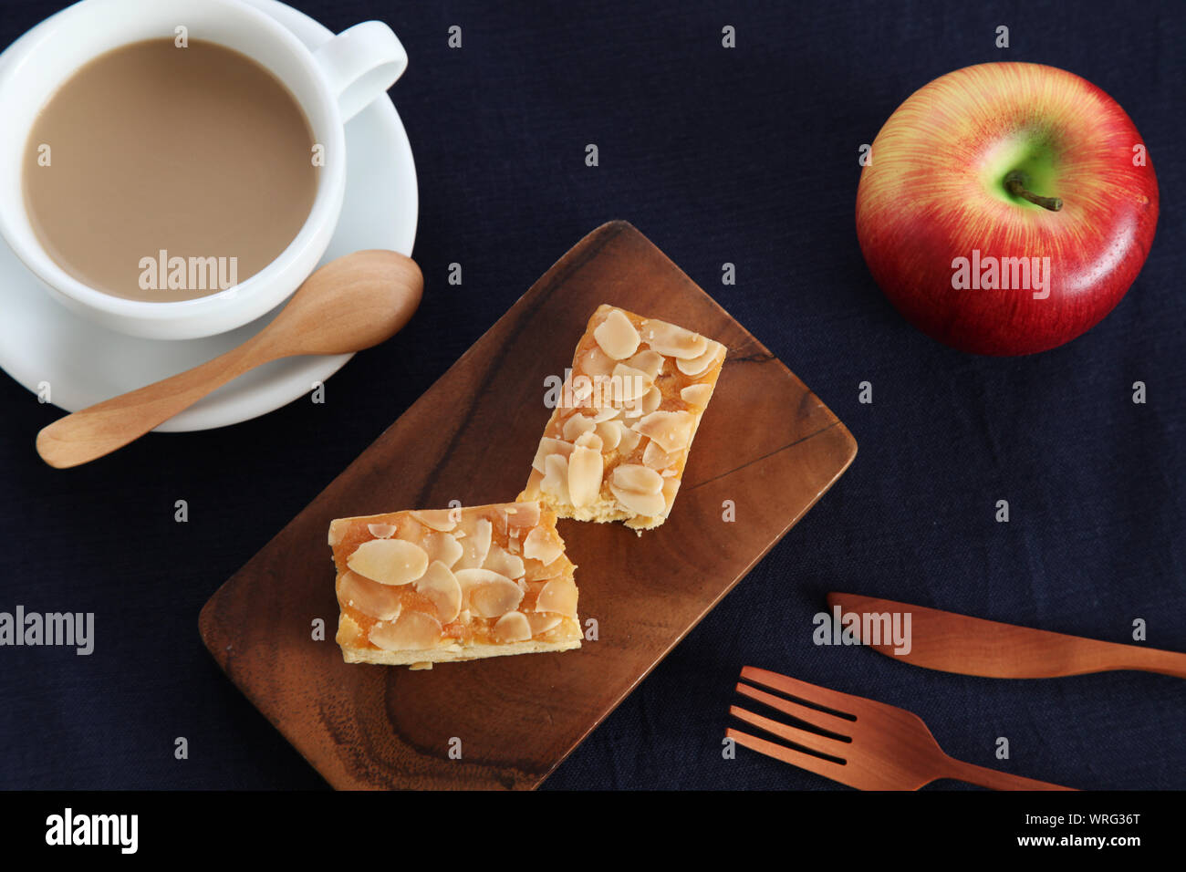 Stück Mandel Apple Pound Cake isoliert auf Schneidebrett und Milch Kaffee auf Holz Tisch Stockfoto