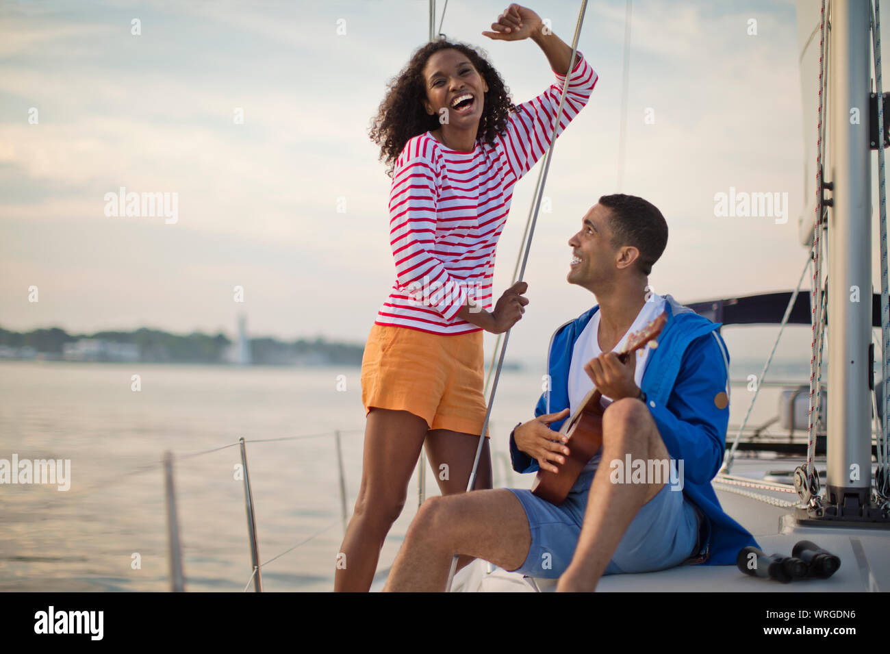 Glückliches junges Paar, das Spaß spielen der Ukulele beim Segeln. Stockfoto