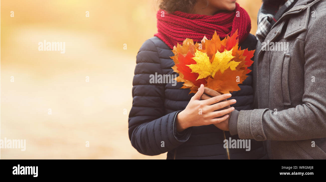 Farben des Herbstes. Paar mit Haufen Blätter Stockfoto