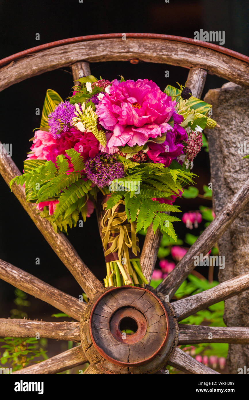 Ein schöner Blumenstrauß aus verschiedenen Blumen auf ein antikes Wagenrad. Stockfoto