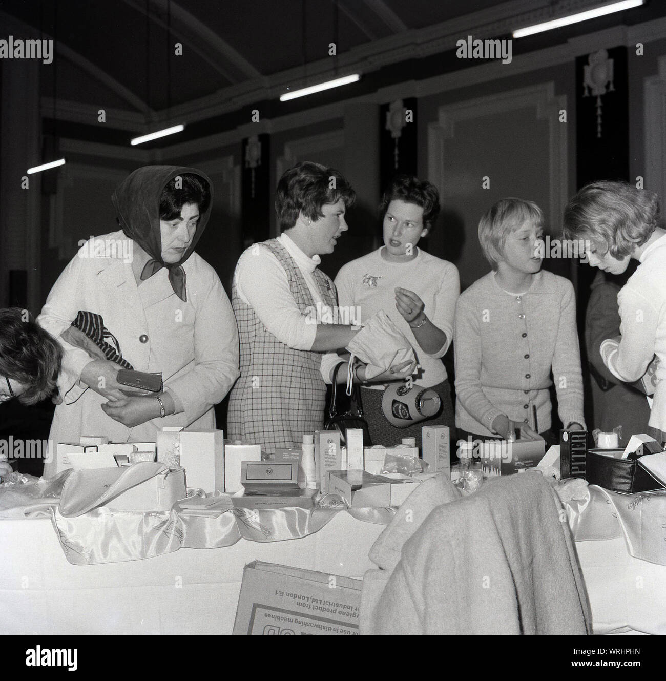 1960, historische, Frauen an einem Parfum Abschaltdruck am Eine fundraising Flohmarkt oder Basar für das St John Ambulance, Großbritanniens führende Erste Hilfe Hilfe und medizinische Wohltätigkeitsorganisation. Stockfoto