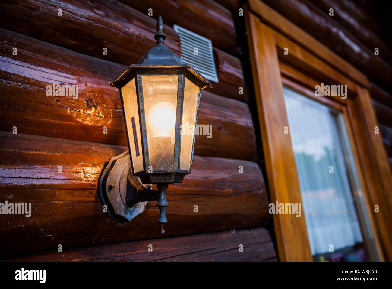 Altmodische Lampe leuchtet auf Holz- Haus, Outdoor. Stockfoto