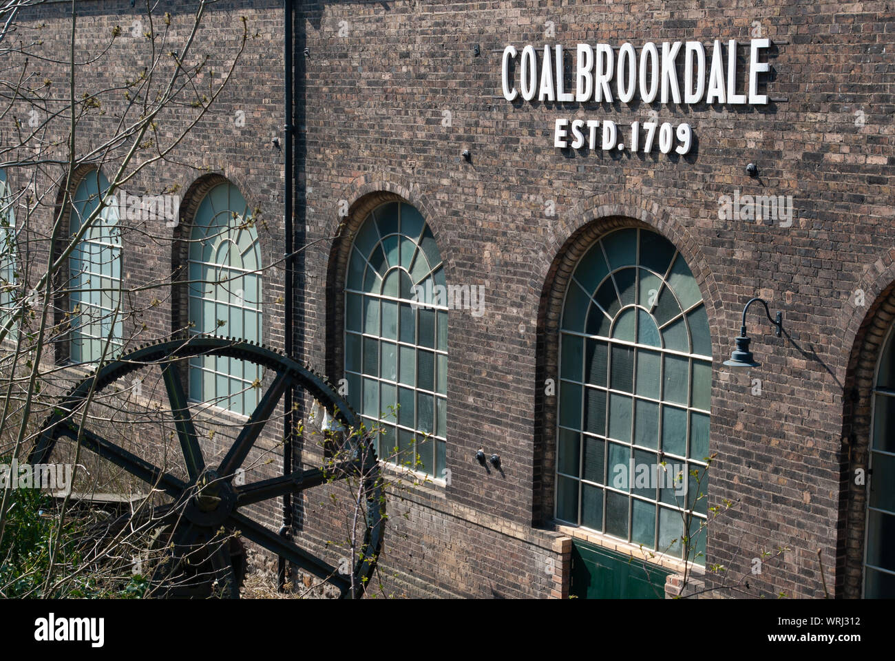 Coalbrookdale arbeitet mit einem großen gusseisernen Rad im Vordergrund und weißen Schildern auf dem Gebäude Stockfoto