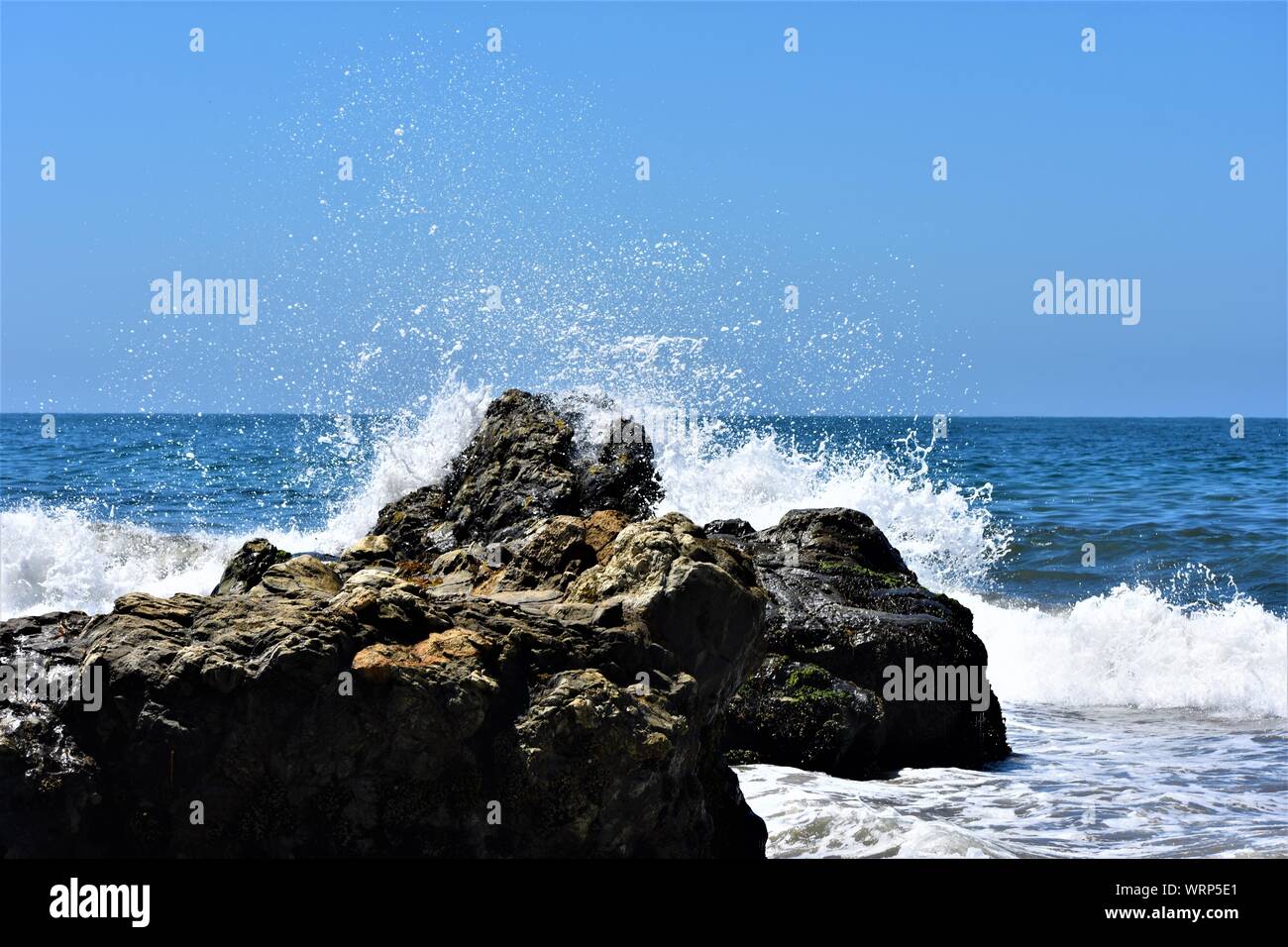Wellen, die auf einem Felsen Stockfoto
