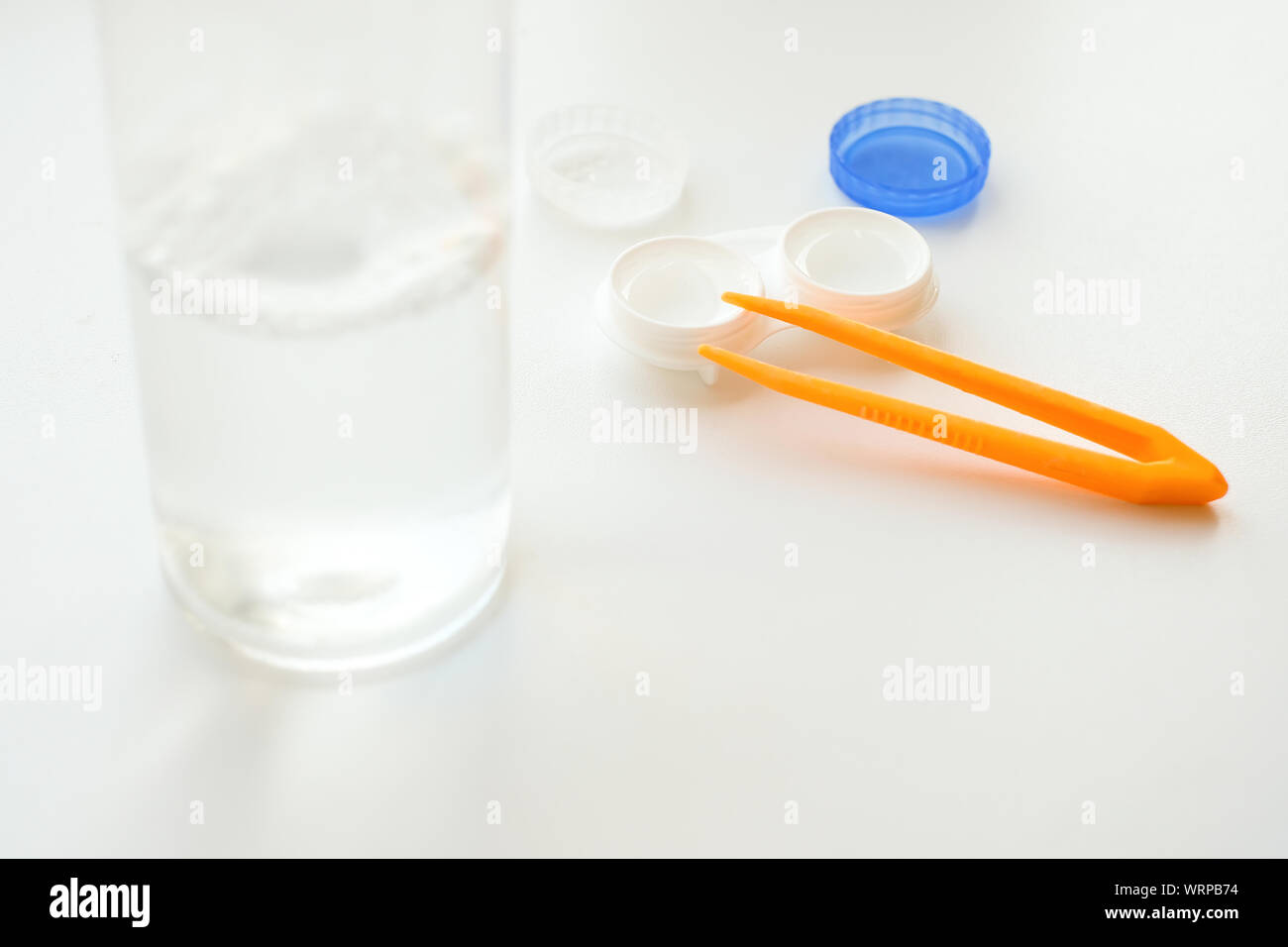 Zubehör für die richtige Verwendung von Kontaktlinsen: Gehäuse, Pinzette und Flasche Lösung auf weißem Hintergrund. Sichere Sehkorrektur. Selektiver Fokus. Stockfoto