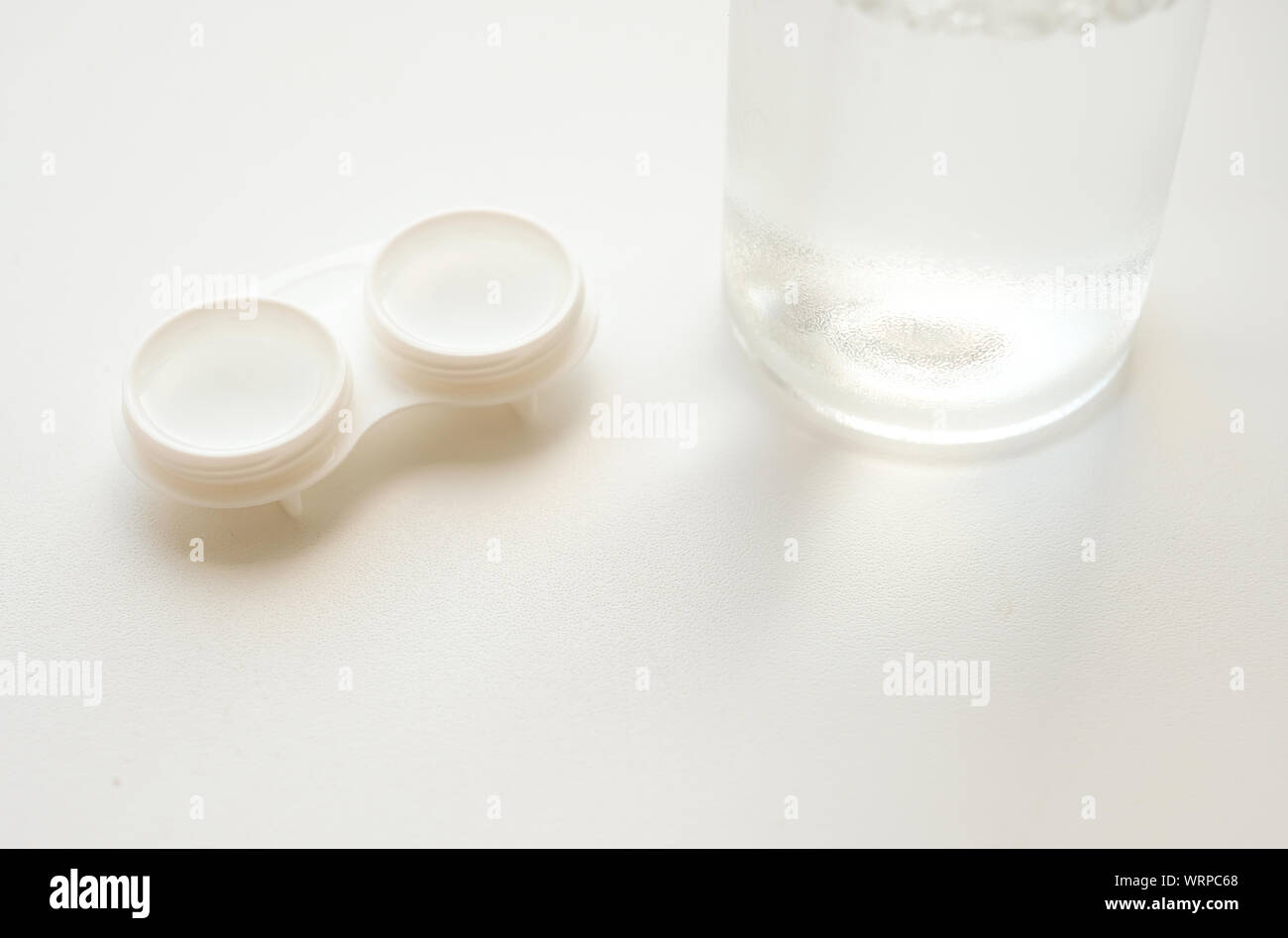 Zubehör für den richtigen Einsatz von weichen Kontaktlinsen: Offenes Gehäuse und Flasche Lösung auf weißem Hintergrund. Sichere Sehkorrektur. Selektiver Fokus. Stockfoto