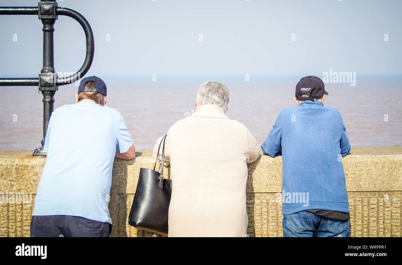 Menschen stehen an der Wand, wie sie die feinen an einem sonnigen Tag am Strand von Withernsea. (Foto von Ioannis Alexopoulos/Alamy) Stockfoto