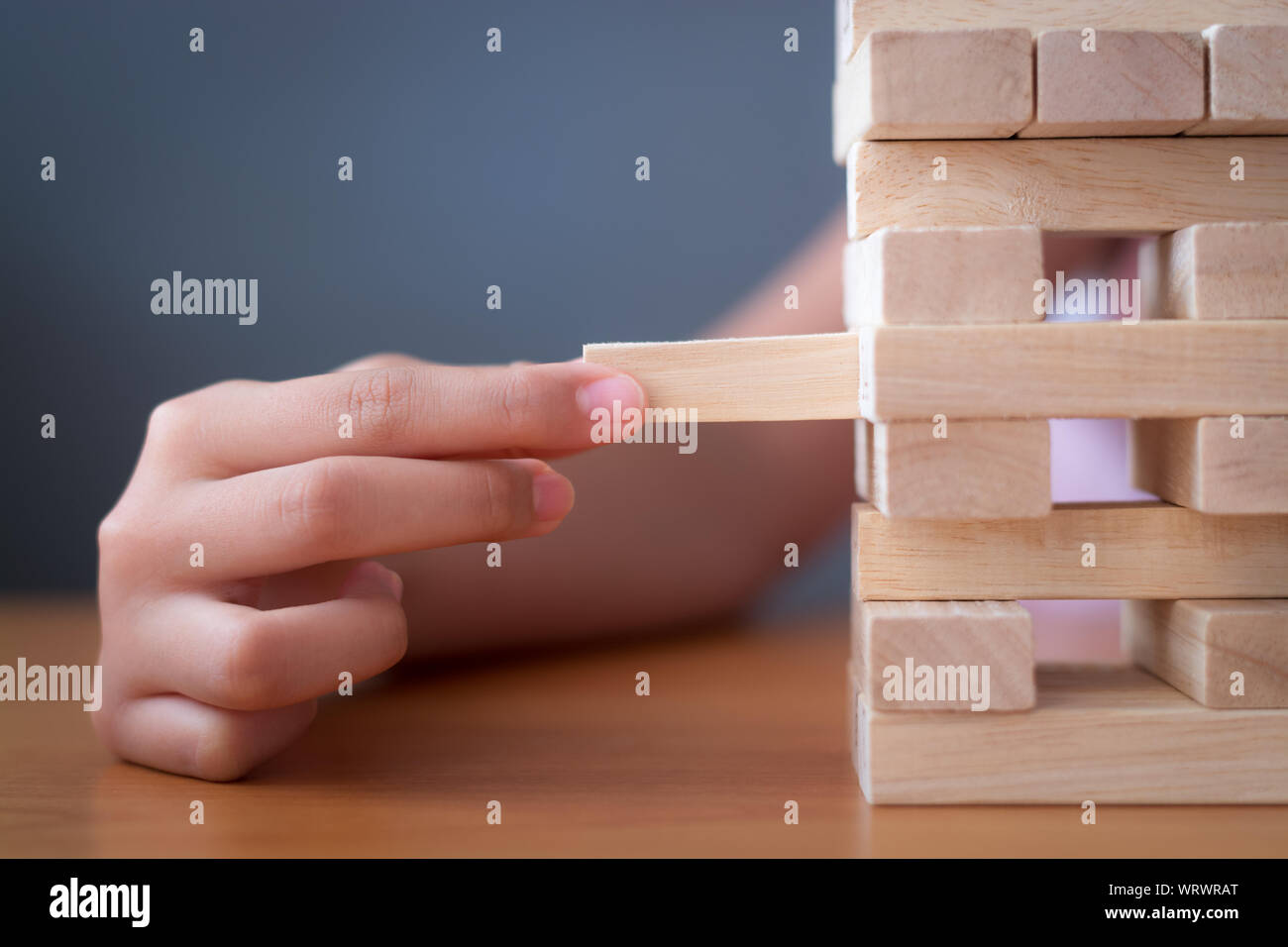 Hand eines Mädchens platzieren und ziehen Holzklotz auf dem Turm. Alternative Risk Konzept, Planung und Strategie im Business und Bildung. Stockfoto