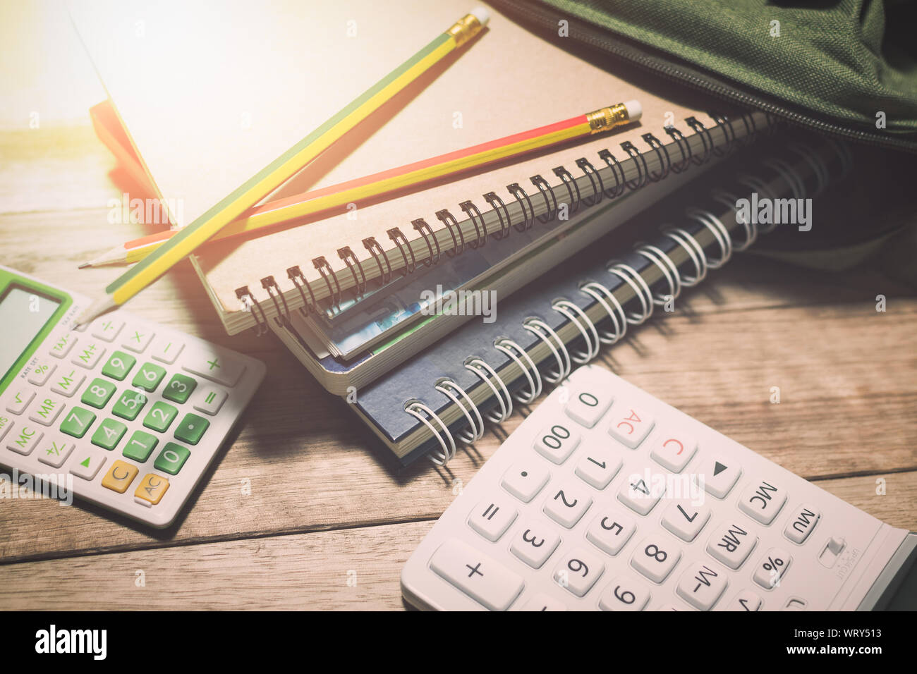 Notebooks in einer mit Bleistift und Taschenrechner auf hölzernen Tisch unter Licht bog, Bildung Konzept. Stockfoto