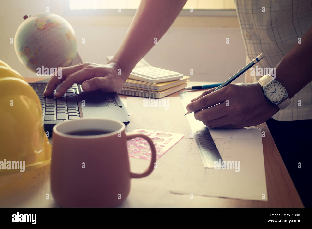 Hand des Architekten Zeichnung bau Plan mit Laptop auf dem Schreibtisch mit strahlend hellen Stockfoto