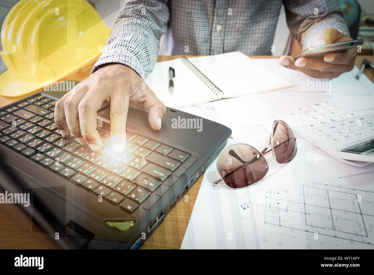 Ein Architekt arbeitet auf beleuchteten Laptop und Handy im Büro Stockfoto