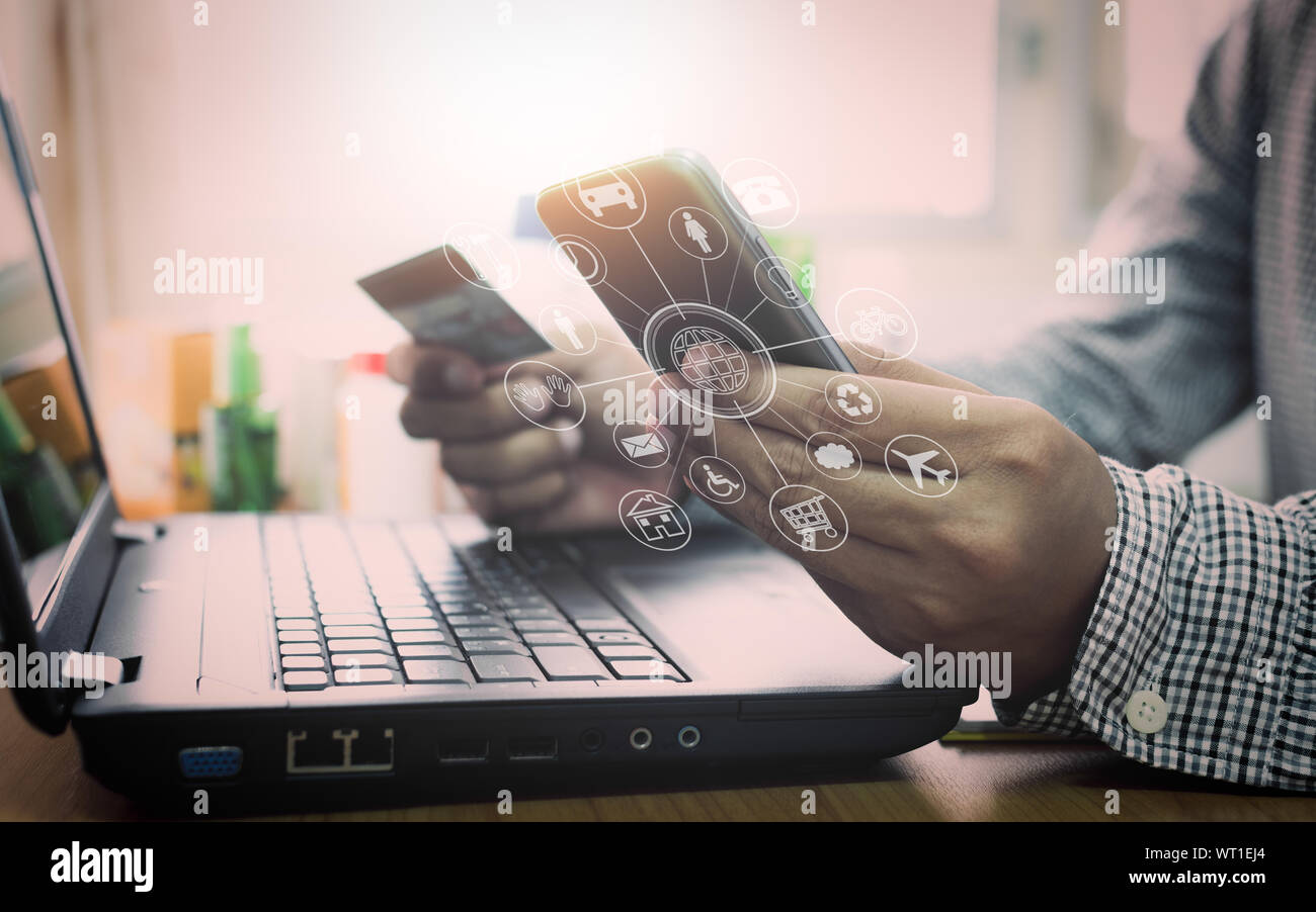 Geschäftsmann mit Laptop und Handy einkaufen und bezahlen per Kreditkarte mit virtuellen grafisches Symbol Diagramm online. Stockfoto
