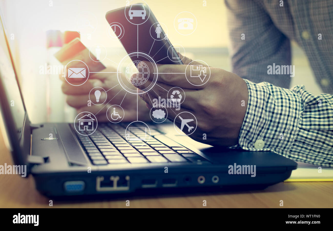 Geschäftsmann mit Laptop und Handy einkaufen und bezahlen per Kreditkarte mit virtuellen grafisches Symbol Diagramm online. Stockfoto